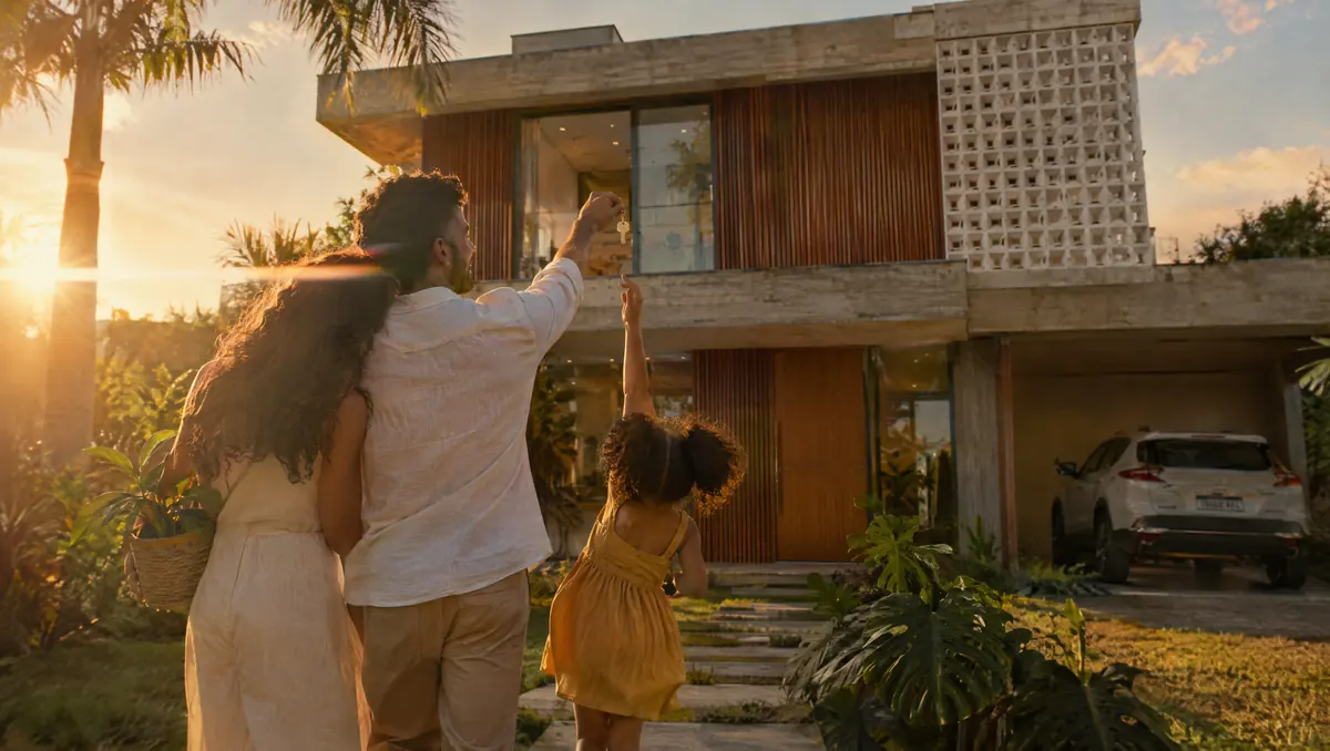 A família de frente para a casa nova ao entardecer, a filha apontando para a janela
